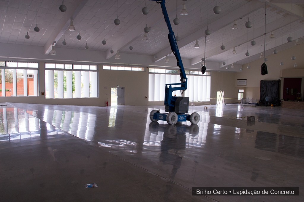 Galpão logístico amplo com piso de concreto polido e plataforma Genie azul